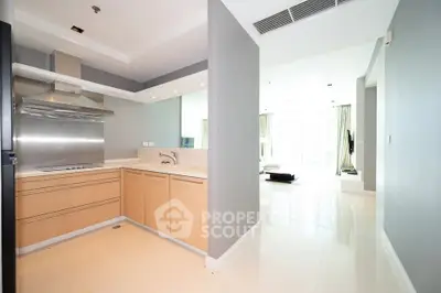 Modern open-layout kitchen with sleek cabinetry and bright living area in luxury apartment.