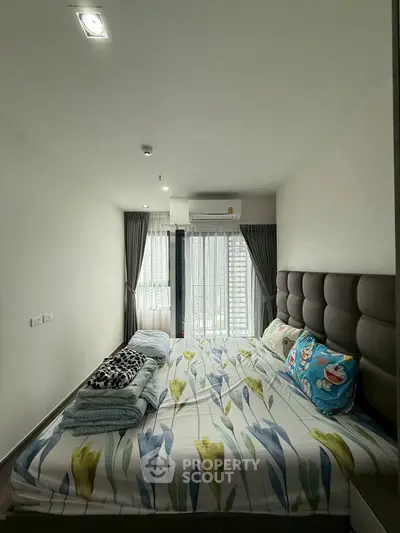 Cozy bedroom with floral bedding and large window offering natural light