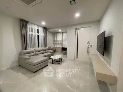 Modern living room with sleek gray sofa and wall-mounted TV in a stylish apartment.