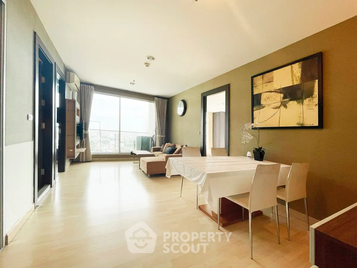 Spacious modern living room with large window and city view, featuring elegant dining area and stylish decor.