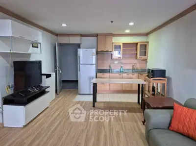 Modern open-layout living room with kitchen, featuring wooden flooring and contemporary furniture.
