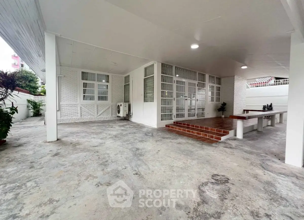 Spacious covered parking area with tiled steps and seating, ideal for gatherings.