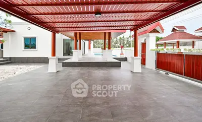 Spacious modern patio with red pergola and sleek tile flooring, perfect for outdoor gatherings.