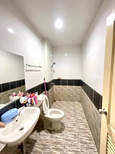 Modern bathroom with tiled walls and floor, featuring a toilet and sink.