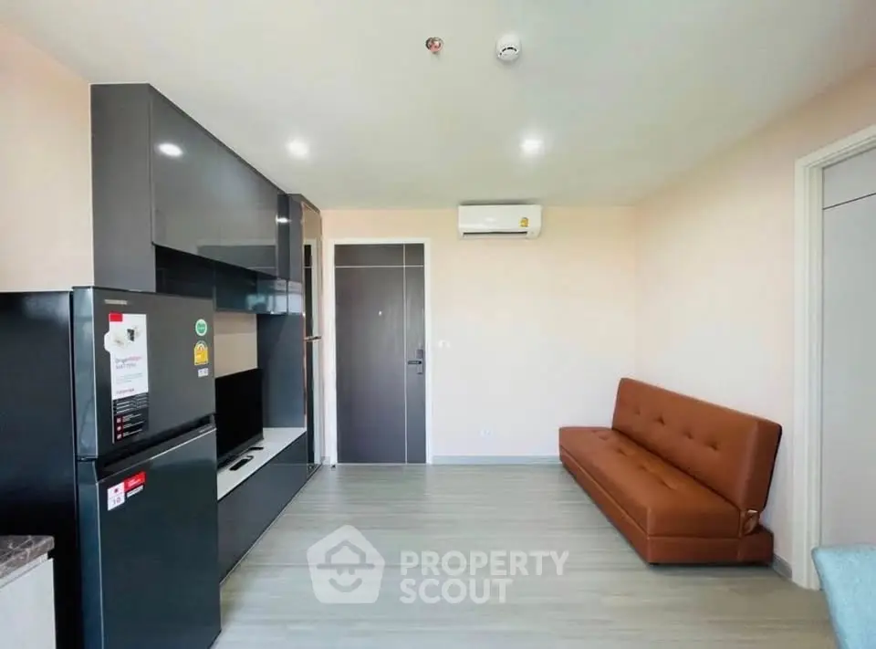 Modern living room with sleek black cabinetry and brown leather sofa, featuring air conditioning and wood flooring.