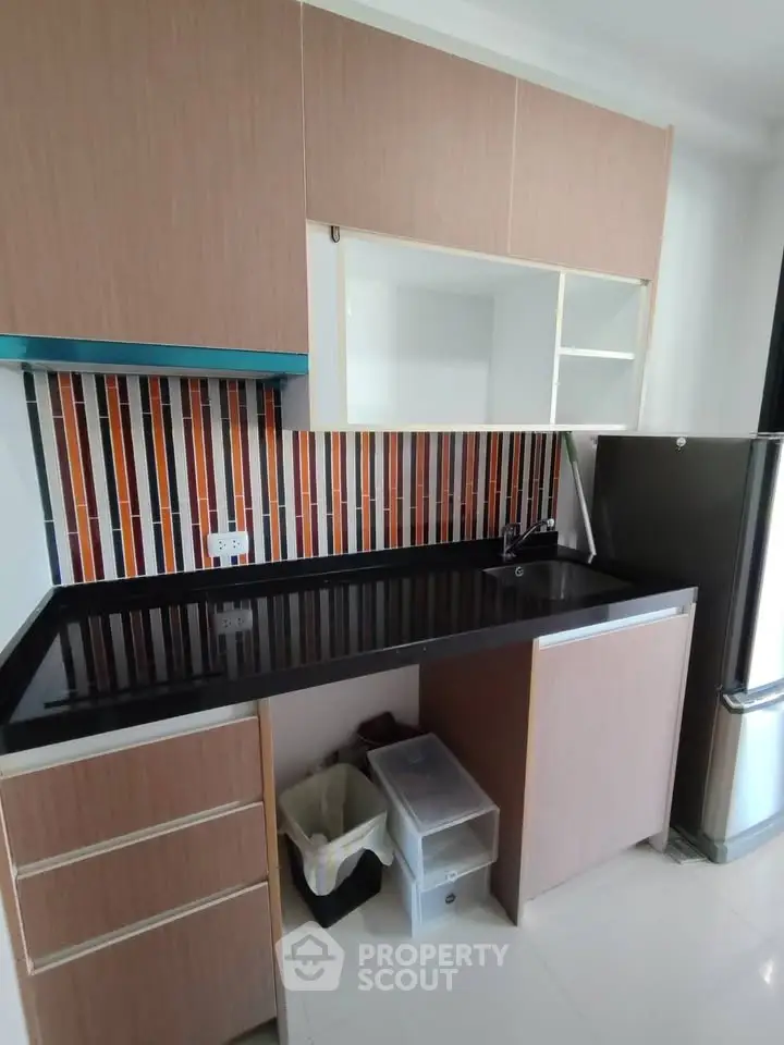 Modern kitchen with sleek cabinetry and colorful backsplash in a contemporary apartment.