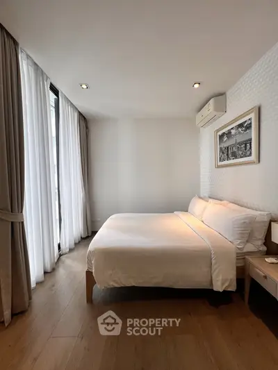 Spacious bedroom with modern decor and large windows for natural light.