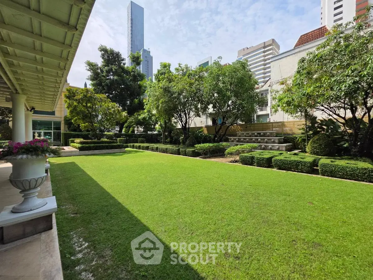 Spacious garden area with lush greenery and cityscape backdrop, perfect for relaxation and outdoor activities.