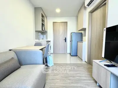 Modern living room with sleek furniture and compact kitchen in a stylish apartment.