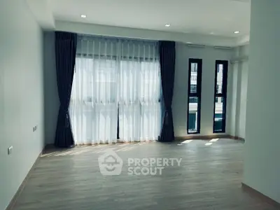 Spacious empty living room with large windows and elegant curtains
