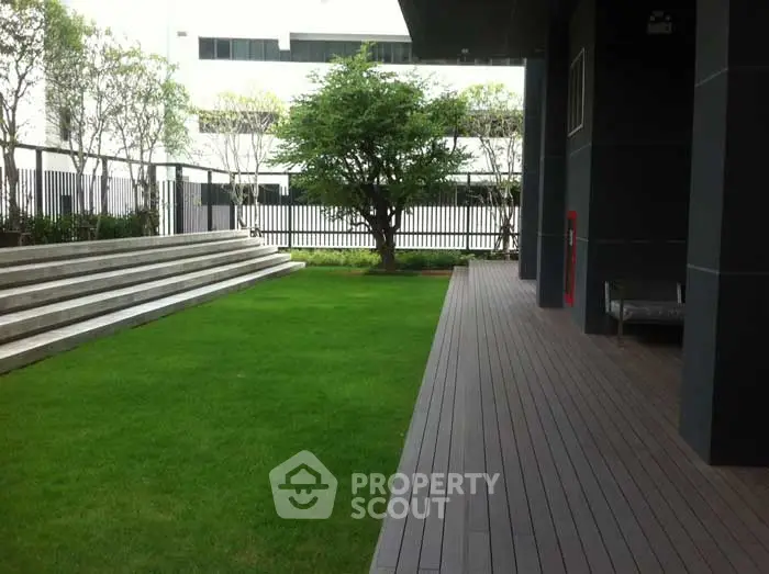 Modern building exterior with lush green garden and wooden deck