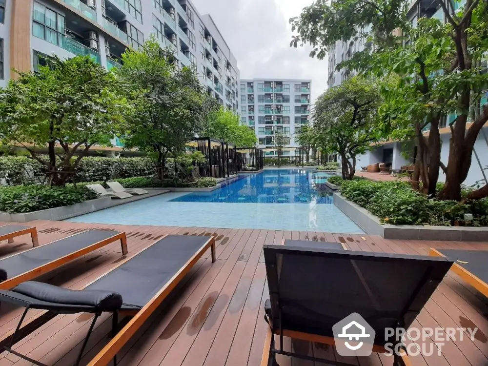 Luxurious condominium pool area with lush greenery and modern sun loungers