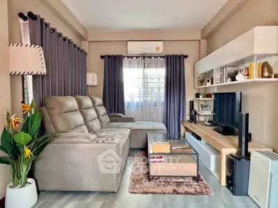 Modern living room with stylish decor, cozy seating, and entertainment center.