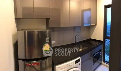 Modern kitchen with sleek cabinets, stainless steel fridge, and washing machine in a compact layout.