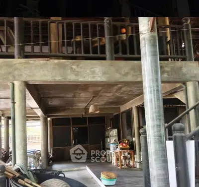 Rustic two-story home with open-air ground floor and wooden railings, showcasing traditional architecture.