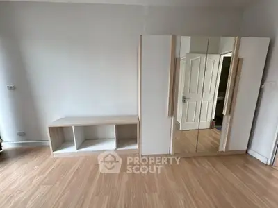 Spacious bedroom with wooden flooring and modern wardrobe design.