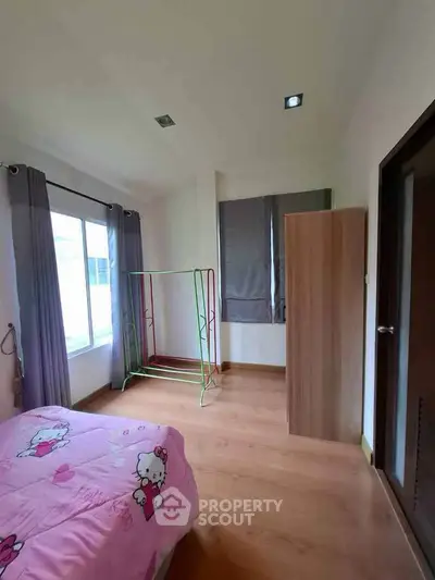 Charming bedroom with wooden flooring and large window, perfect for cozy living.