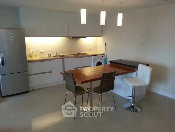 Modern kitchen with sleek appliances and stylish dining area in contemporary apartment.