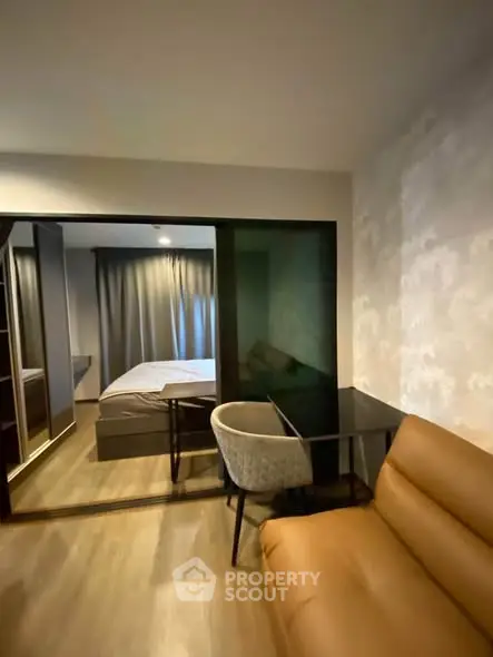 Modern apartment with cozy living area and stylish bedroom separated by sliding glass doors.