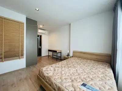 Spacious bedroom with wooden flooring and large window for natural light.