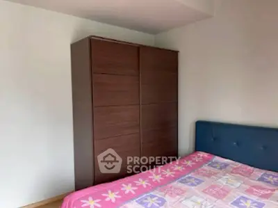 Cozy bedroom with modern wardrobe and colorful bedding in a bright apartment.