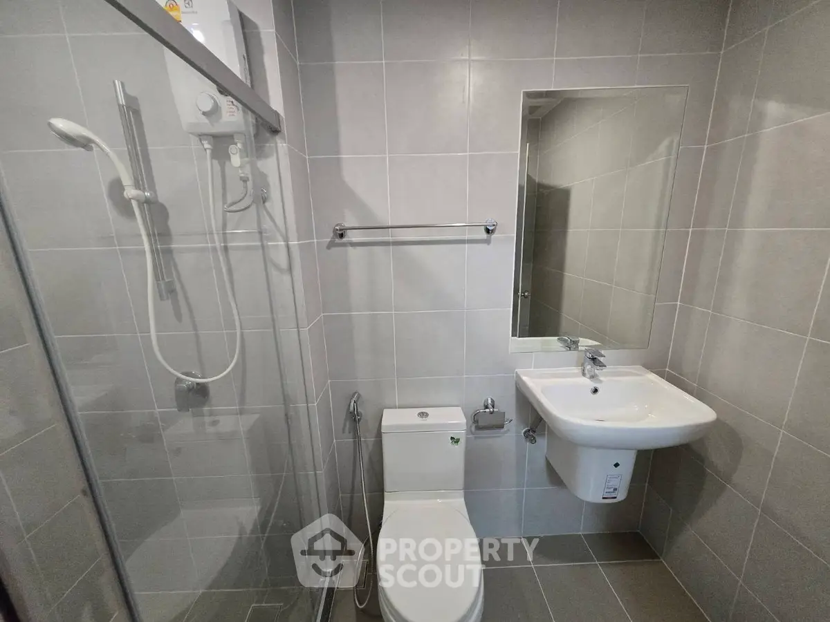 Modern bathroom with sleek tiles, glass shower, and contemporary fixtures.