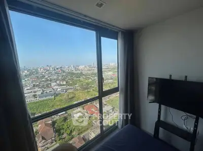 Stunning city view from a modern bedroom with large windows and mounted TV.
