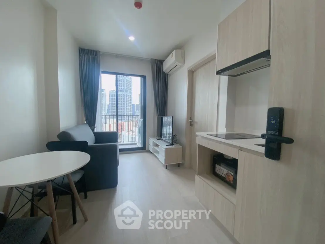 Modern living room with city view, featuring sleek furniture and open kitchen layout.