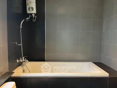 Modern bathroom with sleek bathtub and water heater in stylish tiled design.