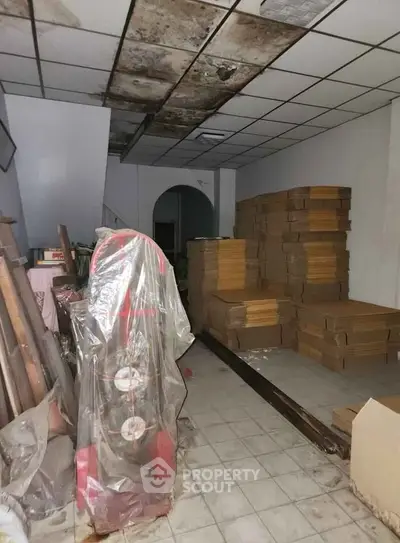 Spacious storage room with stacks of boxes and covered items, ideal for inventory management.