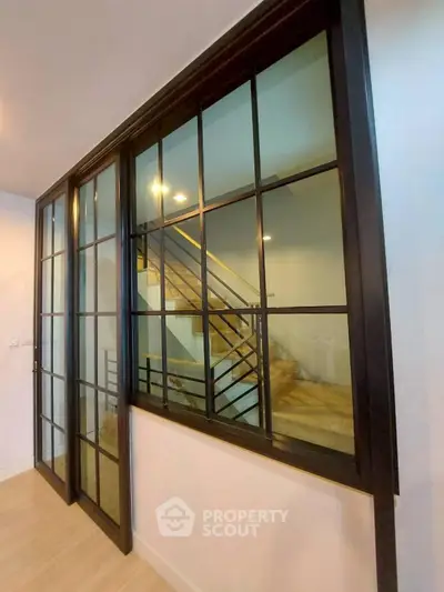 Modern interior with stylish glass partition and wooden staircase