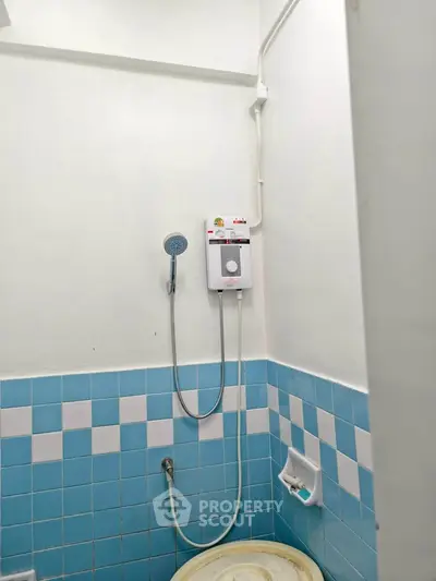 Compact bathroom with blue tile accents and wall-mounted shower heater.
