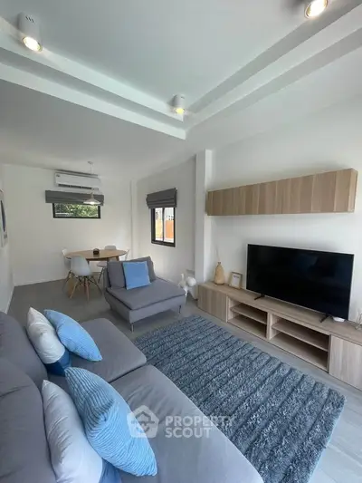 Modern living room with stylish decor, featuring a cozy sofa, flat-screen TV, and elegant dining area.