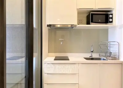 Modern compact kitchen with sleek cabinetry and built-in appliances in a stylish apartment.