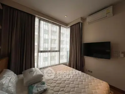 Cozy bedroom with large window and wall-mounted TV in modern apartment.