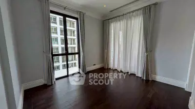 Spacious empty room with dark wood flooring and large windows with curtains, ideal for customization.