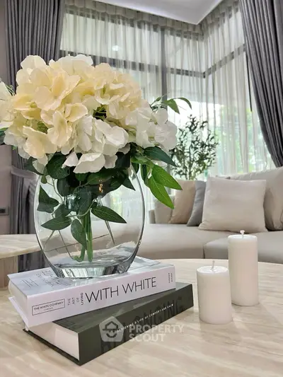 Elegant living room with modern decor, featuring a glass vase with white flowers and stylish books on a coffee table.