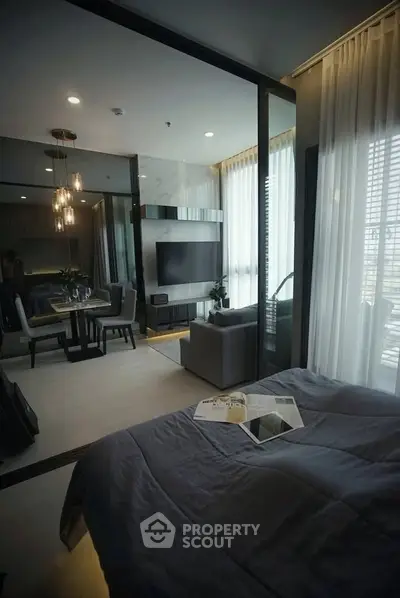Modern open-plan living room with dining area and large windows in a stylish apartment.