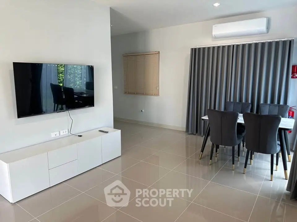 Modern living room with sleek TV setup and elegant dining area, featuring stylish furniture and contemporary design.