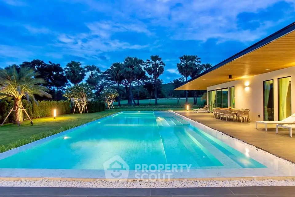 Luxurious modern villa with stunning pool and lush garden view at sunset.
