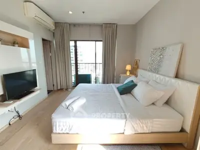 Spacious modern bedroom with large window and stylish decor in a high-rise apartment.