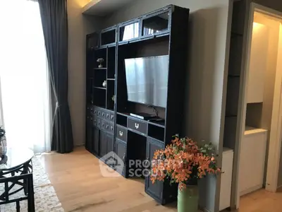 Stylish living room with elegant shelving and large TV, featuring hardwood floors and modern decor.