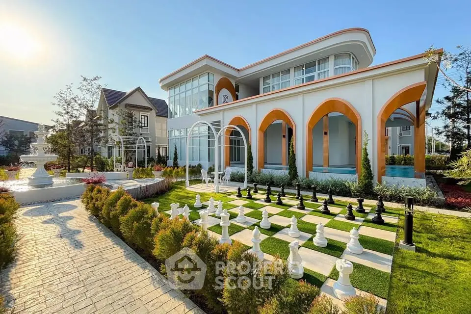 Luxurious modern villa with grand entrance and outdoor chess set in lush garden.