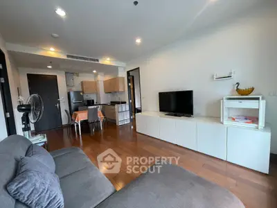 Modern living room with open kitchen, stylish furniture, and hardwood floors in a cozy apartment.