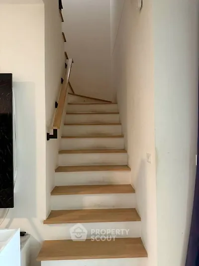 Modern staircase with wooden steps and sleek handrail in contemporary home