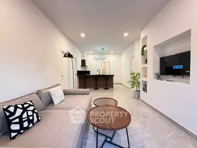 Modern open-plan living room with stylish decor and sleek kitchen area, perfect for contemporary living.