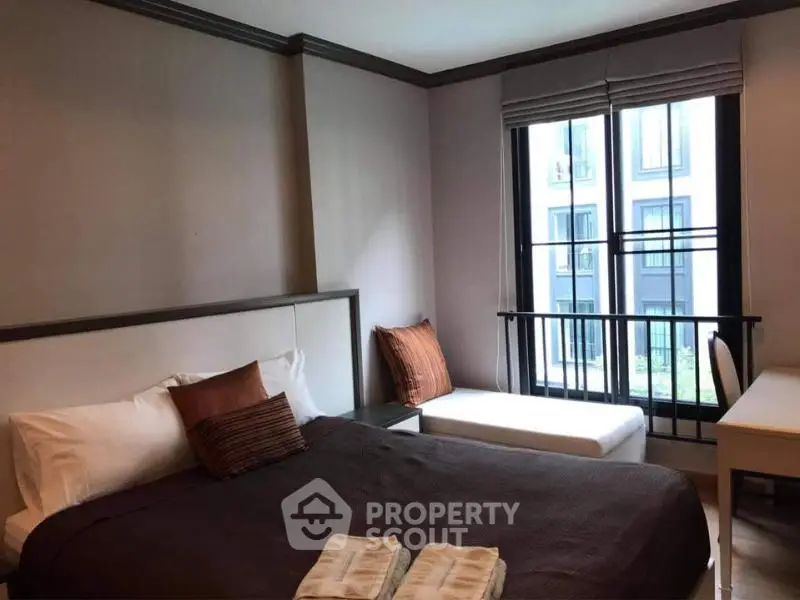 Cozy bedroom with modern decor and large window offering natural light.