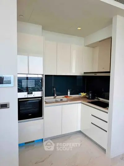 Modern kitchen with sleek white cabinets and built-in appliances in a luxury apartment.