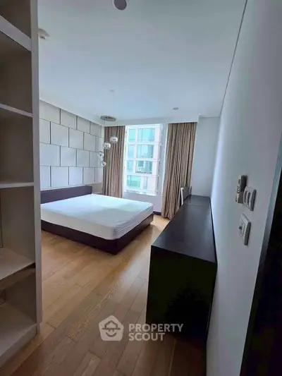 Spacious modern bedroom with large window and wooden flooring in a luxury apartment.