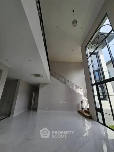 Spacious modern living room with high ceilings and large windows, perfect for natural light and elegant living.